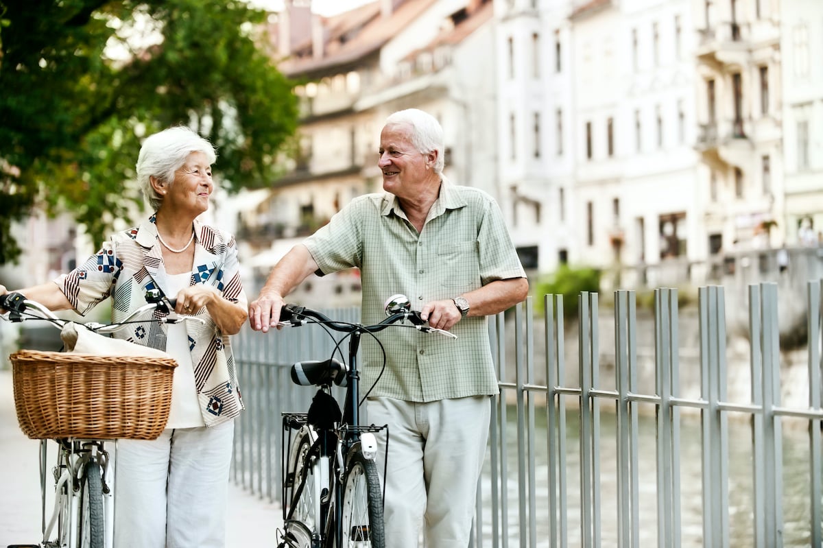 Man and woman walking their bicycles next to a river